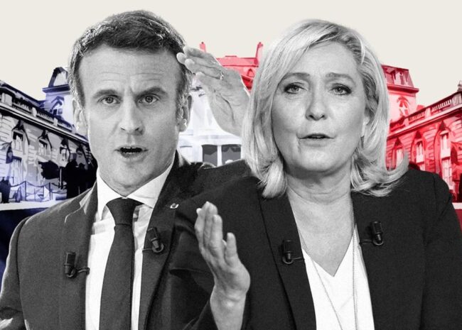 Two politicians in suits speaking on camera, with a red‑blue backdrop behind them, microphones on their jackets.