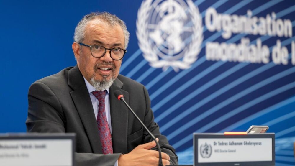 AP26142467553468 - MultiPol 360 Man in a suit and glasses speaks into a microphone at a United Nations press briefing, with the UN emblem in the blue background.